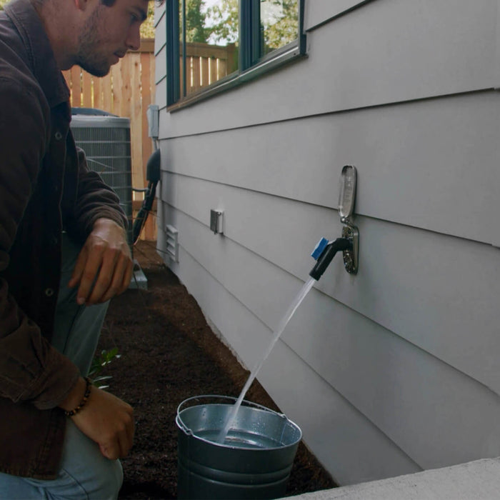 A man watches as he fills a bucket with the jet black removable faucet hose connector plugged into a brushed stainless house hydrant v2+.