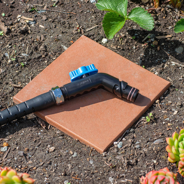 A jet black removable faucet hose connector in a garden.