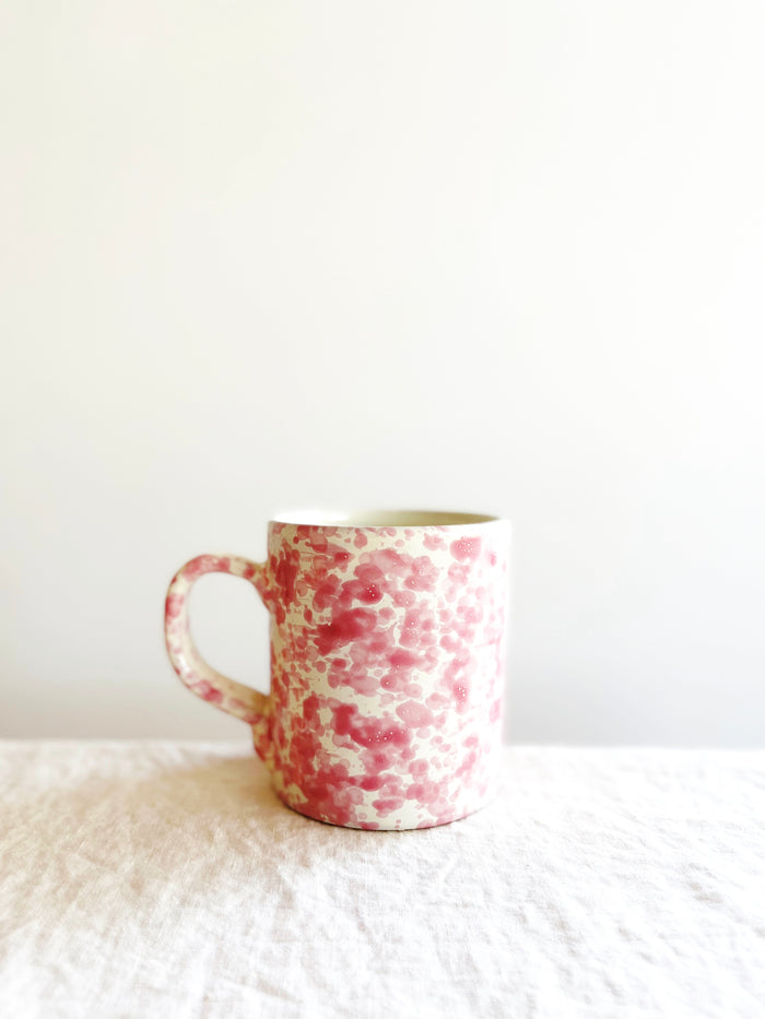 cream mug with pink splatter pattern on white table