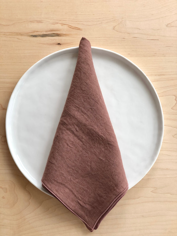 mauve linen rolled edge linen napkins with mauve edge 18 inches square folded on white plate