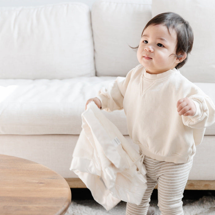 Baby holding a mini blanket with a rich, velvety surface and a satin border, designed to provide warmth and a touch of silky elegance in a small size.