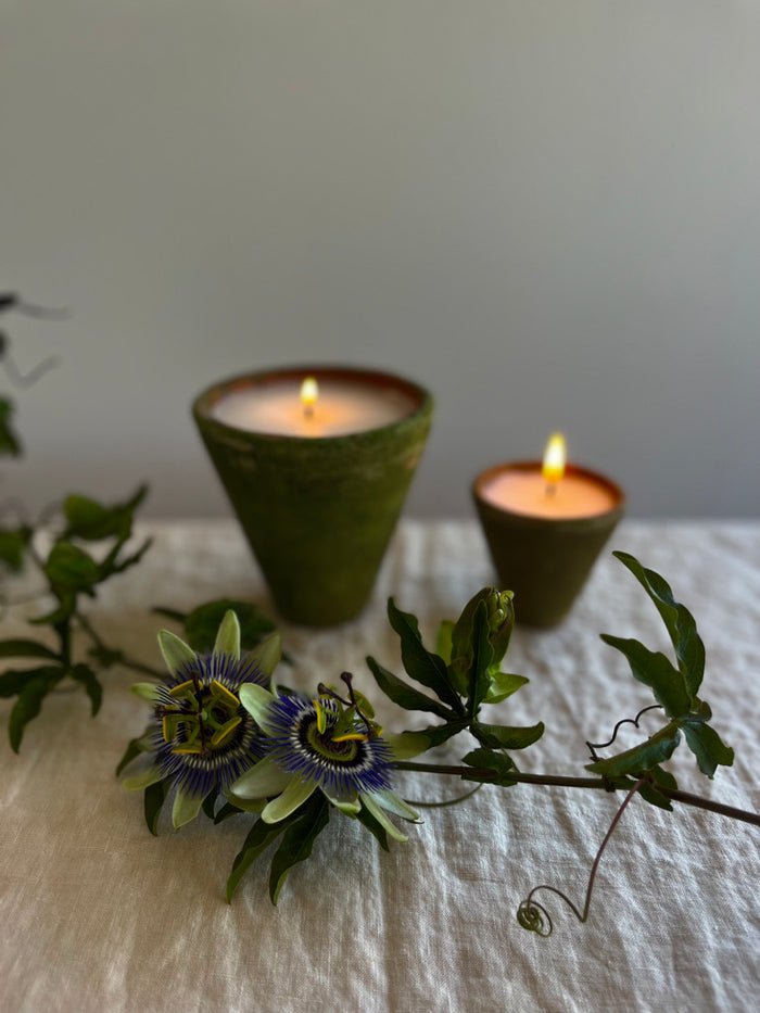 terra cotta candle with a mossy and aged green exterior small and medium on a table